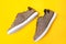 Pair of man's new sneakers made of brown canvas on a yellow background. Side view of shoe. Flat lay