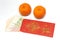 A pair of mandarin oranges and a red envelope with Singapore money notes inside