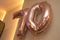 A pair of metallic gold brown colored inflated balloons arranged to show the number seventy