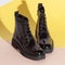 Pair of new black women short boots on medium high heels on beige background studio shot