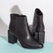 Pair of new black women short boots on medium high heels on beige background studio shot