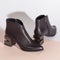 Pair of new black women short boots on medium high heels on beige background studio shot