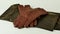 A pair of new brown leather gloves on a green and gold scarf, isolated on a light background. Graceful women's brown