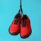 Pair of new red gumshoes hanging on laces on blue background. Urban fashion concept. Closeup