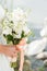 A pair of newlyweds with a bouquet of white roses sits near the lake. swan swims