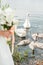 A pair of newlyweds with a bouquet of white roses sits near the lake. swan swims