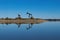 Pair of oil pump jacks on rocky peninsula in glassy calm lake