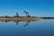 Pair of oil pump jacks on rocky peninsula in glassy calm lake