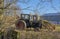 A Pair of Old unused Tractors, parked up in light Woodland next to a Modern barn at a Farm at the Mains of Arbilot.