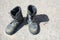 Pair of old used work boots on concrete background. Dirty black leather boots from the army