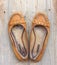 A pair of old worn orange female shoes made of genuine leather on old gray wooden board
