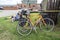 Pair of old yellow bikes leaning against a fence while their riders take a break