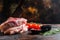 Pair organic raw pork chops arranged for cooking over wooden table and rustic backdrop and chopping cleaver butcher knife, side