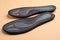 Pair of orthopedic insoles on pale orange background