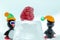 A pair of penguins made from Venetian glass in front of frozen raspberry on the ice cube.
