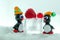 A pair of penguins made from Venetian glass in front of frozen raspberry and red currant on the ice cube.
