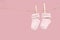 Pair of pink baby socks on a clothesline on a pink background