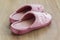 Pair of pink female house slippers on a brown wooden floor. Cozy, warm and comfortable domestic shoes