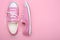 Pair of pink female sneakers on pink background