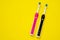 Pair of pink for girl and black for boy electric toothbrushes with replacement heads, top view, copy space.