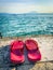 a pair of Red bathing slippers stand on the shore of Lake Garda
