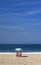 Pair of red beach chair and a blue beach parasol on the sandy beach facing blue ocean and sky