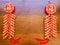 A pair of red firecracker decorations on wooden brown background.