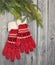 A pair of red gloves hanging on wooden background