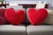 a pair of red love heart shaped cushions on a comfy sofa