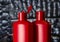 Pair of red plastic bottles open and closed from under a cosmetic product on a charred wood background