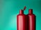 Pair of red plastic bottles open and closed from under a cosmetic product on a green background