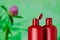 Pair of red plastic bottles from under a cosmetic product on a green background with an blurred image of clover