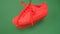 Pair of red sneakers hanging on green background. Orange boots hang out on the rope