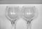 A pair of red wine glasses with reflections presented in monochrome