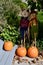 Pair of scarecrows and 3 large pumpkins in a row on walkway