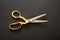 Pair of scissors gold handle on black background, top view