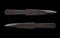 A pair of scratched steel throwing knives on black background