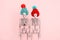 pair of  skeletons wearing cute knitted hat on a pink background