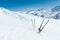 A pair of skis and ski poles stick out in the snow on the mountain slope of the Caucasus against the backdrop of the