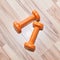 Pair of small orange rubberized dumbbells on the floor