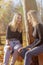 Pair of smiling attractive young girls sitting outdoors