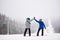 Pair of snowboarders with giving high five standing on ski run. Dense foggy views in snowfall on background