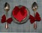 A pair of spoons with red ribbon and red heart on a plate. Valentine\'s Day