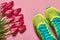 Pair of sport shoes and tulips on pink pastel background. New sneakers, copy space. Overhead shot of running foot wear. Top view