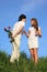 Pair stands, guy holds behind back bouquet