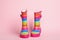 Pair of striped rubber boots on pink background