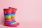 Pair of striped rubber boots on pink background. Space for text