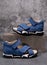 Pair of stylish blue children's sports sandals for boys on gray concrete background.