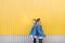 Pair of stylish people standing backs against the background of the yellow wall. Hipsters photo