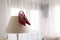 Pair of stylish red shoes carefully placed on a modern lamp